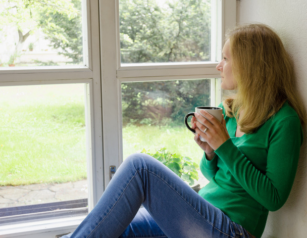 σπασμένη καρδιά κορίτσι κάθονται στο παράθυρο περβάζι ποτό καφέ  - Φωτογραφία, εικόνα
