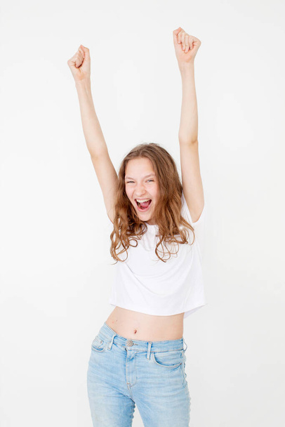 Portrait of young beautiful cute cheerful girl smiling looking at camera over white background. Happy winner teen  in white t-shirt - Foto, Bild