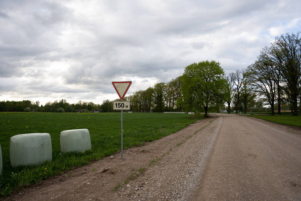 estrada rural arenosa com um sinal de estrada dar lugar - Foto, Imagem