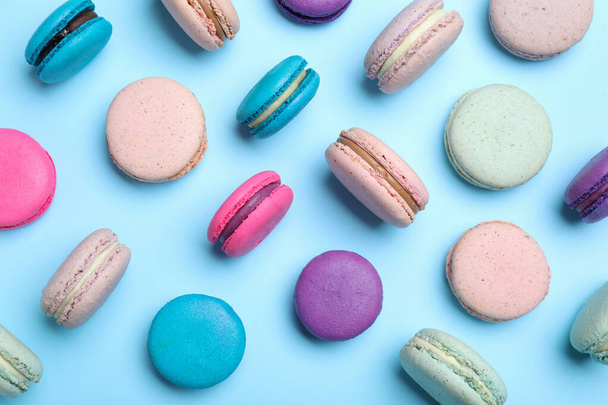 Delicious colorful macarons on light blue background, flat lay - Foto, imagen