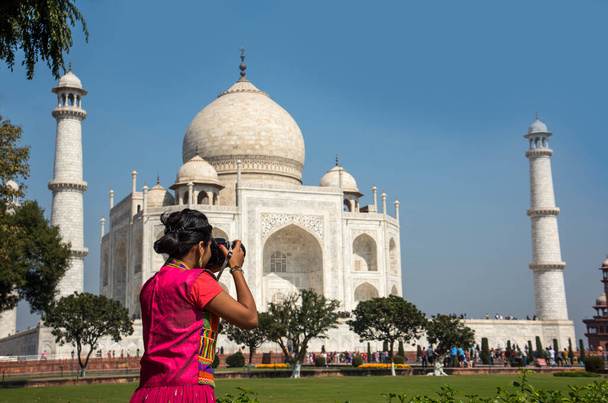 Νεαρό κορίτσι με παραδοσιακά ρούχα φωτογραφίζει το Taj Mahal στην Agra της Ινδίας. - Φωτογραφία, εικόνα