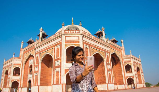 Donna indiana scattare selfie con smartphone di fronte alla tomba di Humayun, Delhi, India, Patrimonio dell'Umanità UNESCO.  - Foto, immagini