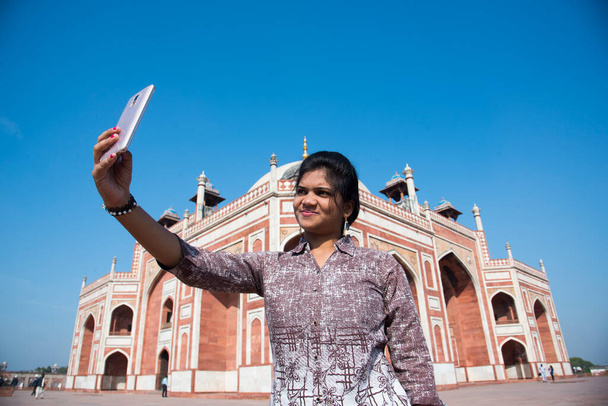 Donna indiana scattare selfie con smartphone di fronte alla tomba di Humayun, Delhi, India, Patrimonio dell'Umanità UNESCO.  - Foto, immagini