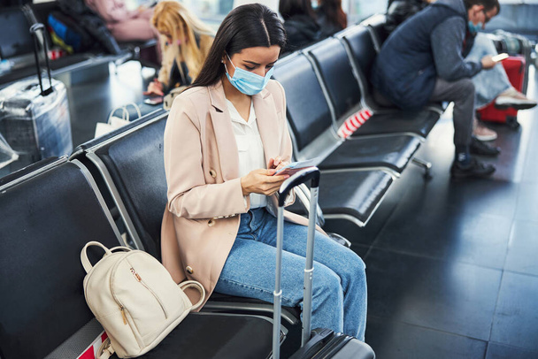 Elegant woman in medical mask waiting for the flight at airport - Foto, Imagen