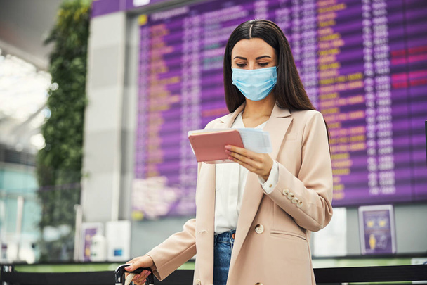 Viajante feminino em máscara médica esperando o voo no aeroporto - Foto, Imagem