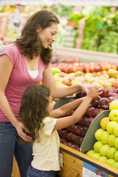 Mother and daughter in produce section of supermarket - Photo, image