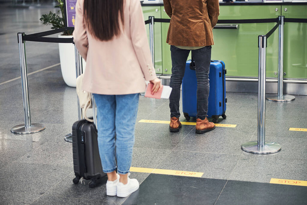 Young man and woman standing in queue at airport - 写真・画像