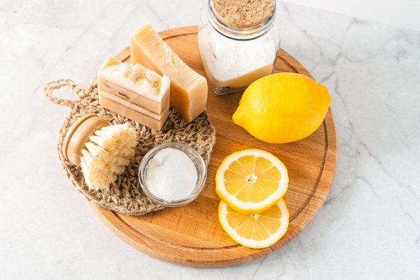 Eco friendly natural cleaners, jar with baking soda, dish brush, lemon, soap on white marble table background. Organic ingredients for homemade cleaning. Zero waste concept - Photo, Image