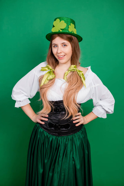 Woman in green hat, black corset and white shirt posing isolated on green background. St. Patrick's Day and Oktoberfest celebration concept. - Photo, Image