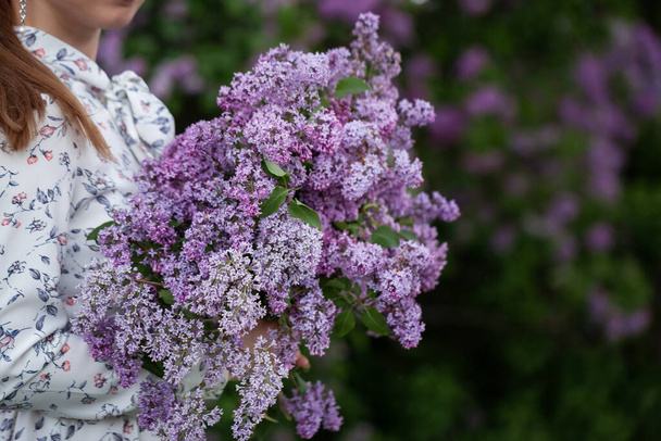 Close-up woman with a purple bouquet of Lilacs. Girl holding large bouquet of purple flowers in her hands. - Fotografie, Obrázek