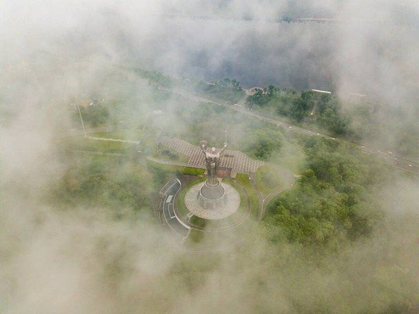 Motherland monument in Kiev between the clouds. Aerial drone view. - Photo, Image