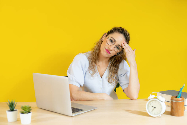 Ανήσυχη γυναίκα που εργάζεται σε φορητό υπολογιστή πάνω από κίτρινο φόντο. - Φωτογραφία, εικόνα
