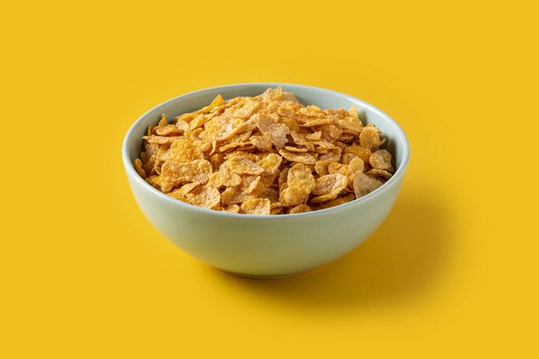 Corn flakes in a blue bowl on yellow background - Photo, Image