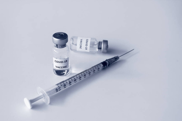 Beyaz arka planda izole edilmiş Covid-19 aşısı şişesi ve 1 ml plastik şırınga. - Fotoğraf, Görsel