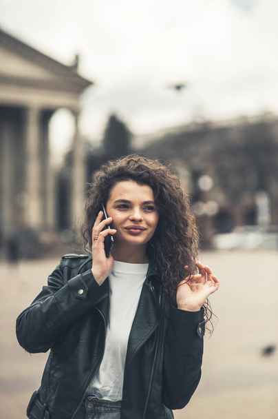 Portrait of attractive curly hairstyle dark skin person speak phone toothy smile free time weekend walking outdoors - Foto, immagini