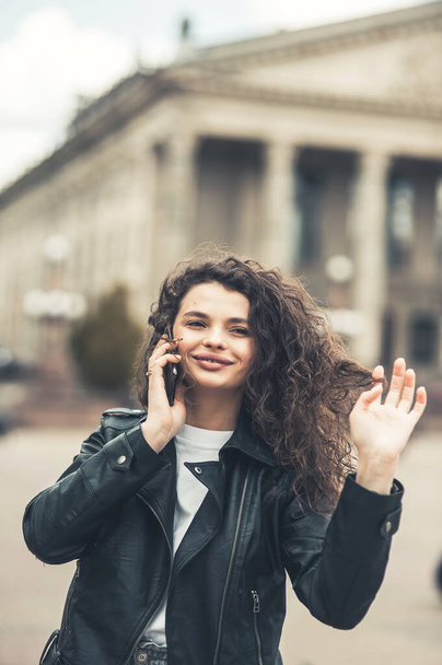 Portrait of attractive curly hairstyle dark skin person speak phone toothy smile free time weekend walking outdoors - Foto, Imagen