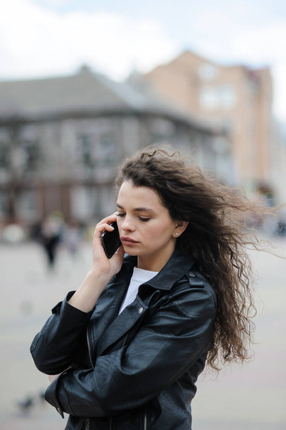 Beautiful brunette on the street talking on the phone. - Zdjęcie, obraz