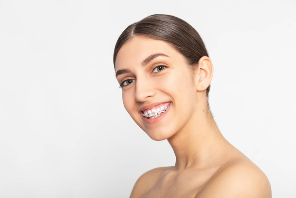 Close up portrait of Smiling Teen girl showing dental braces.Isolated on white background. - Fotografie, Obrázek