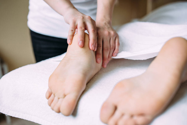 De masseur geeft een massage aan de vrouwelijke voeten in de spa. - Foto, afbeelding