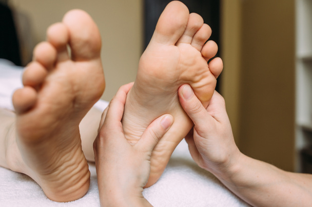 The masseur gives a massage to the female feet at the spa. - 写真・画像