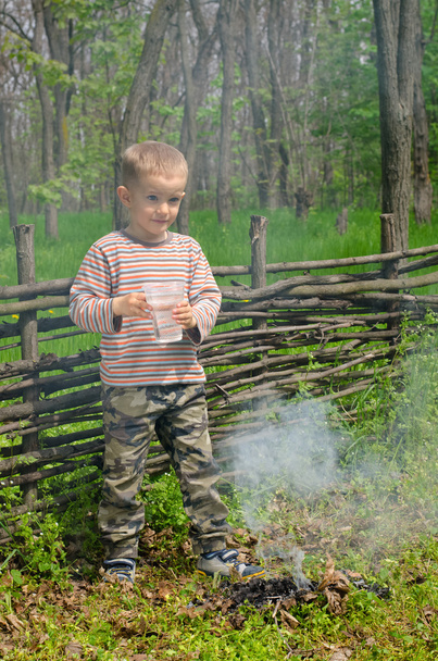 Petit garçon éteignant un feu de camp
 - Photo, image