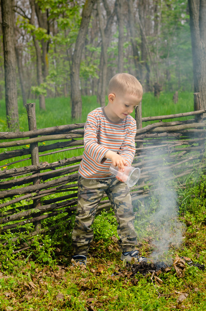 小さな男の子のキャンプの火を消す - 写真・画像