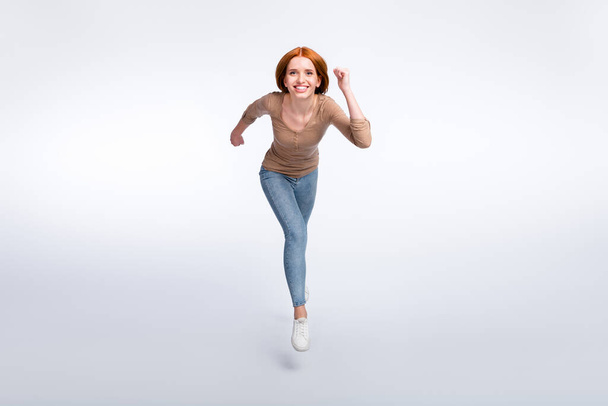 Full length photo of funky pretty redhair woman beige shirt jumping high running fast isolated white color background - Fotó, kép