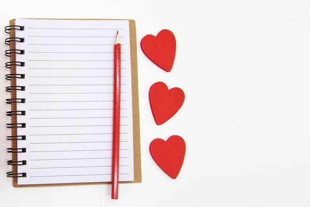 A notebook with blank sheets,a red pencil, hearts on a white background.The concept of writing in a notebook in the first person, planning, making a to-do list, greeting for the celebration.Copyspace. - Foto, Imagem
