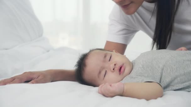 Fiatal ázsiai anya csók arc kisbaba lány gyengéd az ágyban a hálószobában, anya szerelem újszülött és gondozás, anya kifejezéssel gyermek együtt, szülő és lánya, családi koncepció. - Felvétel, videó
