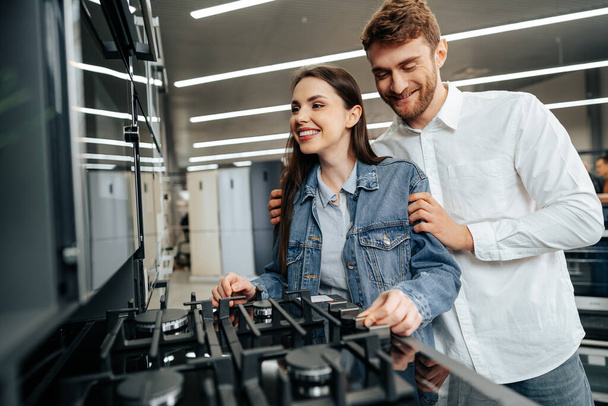 Young couple choosing new gas stove in home appliances store - Foto, Bild