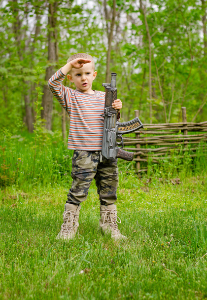Garçon portant une mitrailleuse saluant
 - Photo, image