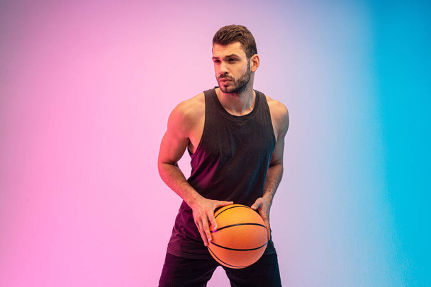 Concentrated young man play basketball in studio - Foto, afbeelding