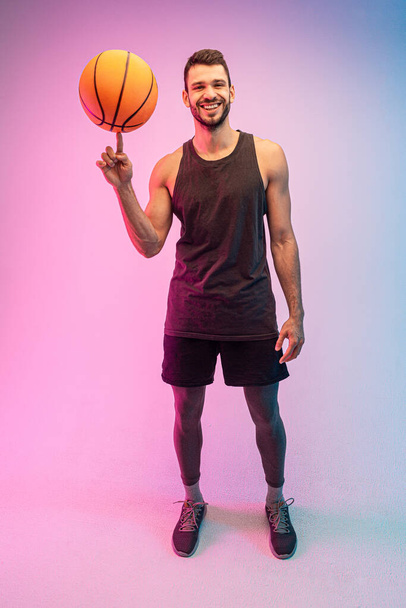 Genç sporcu parmak üstünde basketbol topu çeviriyor. - Fotoğraf, Görsel