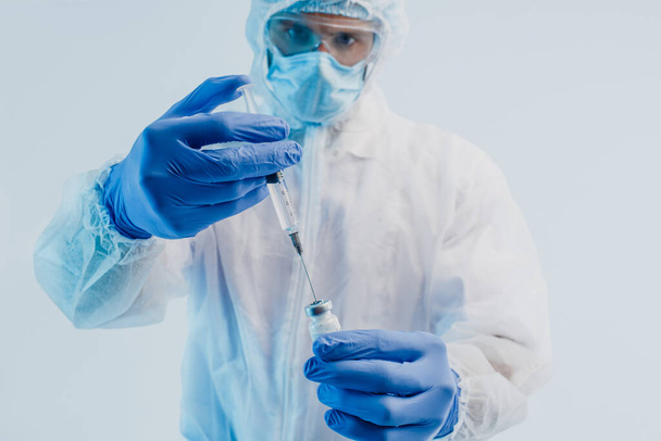 Чоловік-лікар наливає вакцину проти COVID-19 до шприца
 - Фото, зображення