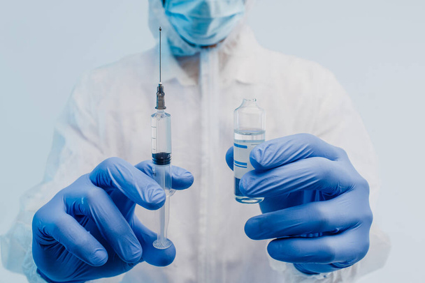 Male doctor showing COVID-19 vaccine and syringe - Φωτογραφία, εικόνα