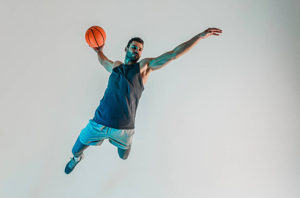 Αθλητής πηδάει και θέλει να ρίξει μπάλα μπάσκετ - Φωτογραφία, εικόνα