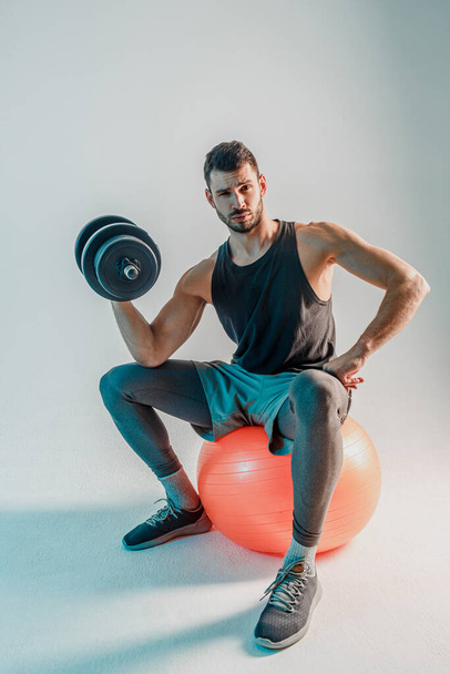 Sportsman training biceps with dumbbell in studio - Foto, afbeelding