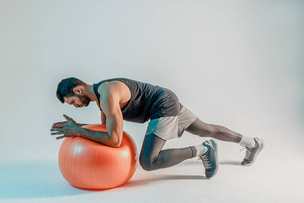 Спортсмен отжимается на фитнес-мяч - Фото, изображение