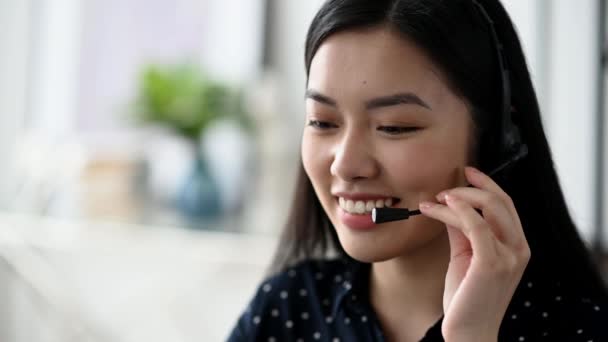 Lähikuva kaunis luottavainen pitkäkarvainen nuori aasialainen nainen kuulokkeet, freelancer, Call Center työntekijä tai konsultti, yllään musta tyylikäs paita, puhuu kautta online-viestintä, hymyilevä ystävällinen - Materiaali, video