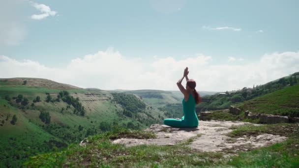 Dziewczyna ćwiczy jogę siedząc w pozycji lotosu Piękny krajobraz górski - Materiał filmowy, wideo