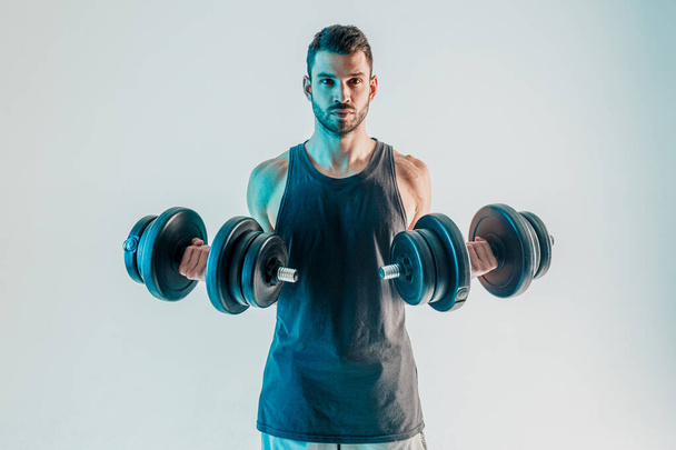 Młody mężczyzna trenuje mięśnie bicepsów z hantlami - Zdjęcie, obraz