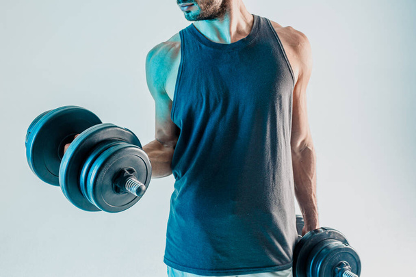 Young man training biceps muscles with dumbbells - Photo, Image