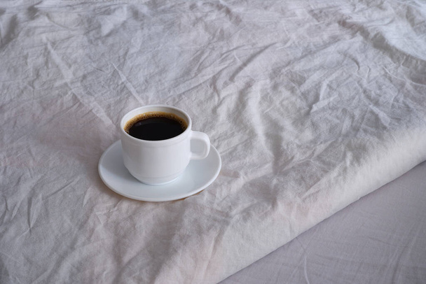 White cup of black coffee in a white bed. - Zdjęcie, obraz