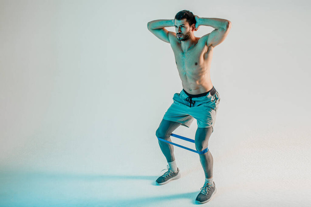 Молодой спортсмен тренирует ноги с полосой сопротивления - Фото, изображение