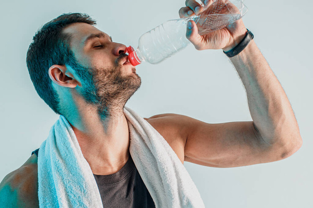 Tired young sportsman drinking water from bottle - Φωτογραφία, εικόνα