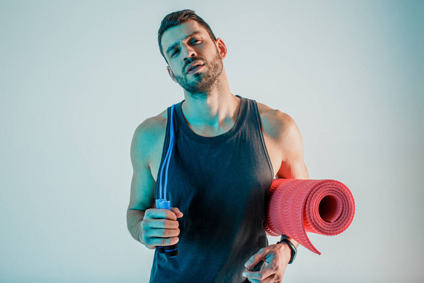 Sportsman with skipping rope and fitness mat - Photo, Image