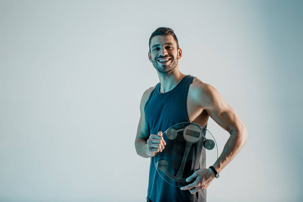 Cheerful sportsman hold weight scales in studio - Photo, Image