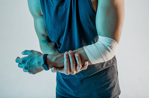 Ο αθλητής κρατάει το τραυματισμένο του χέρι στο στούντιο. - Φωτογραφία, εικόνα