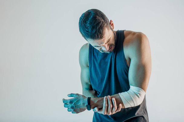 Uupunut urheilija pitää loukkaantunut käsi studiossa - Valokuva, kuva