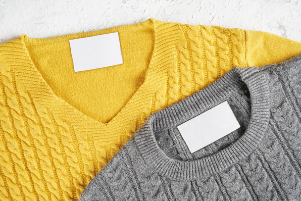 Mockup wewnętrznej etykiety na szyjach ładnych szarych i żółtych wełnianych swetrów. Puste miejsca do umieszczenia logo, tekstu lub obrazu - Zdjęcie, obraz